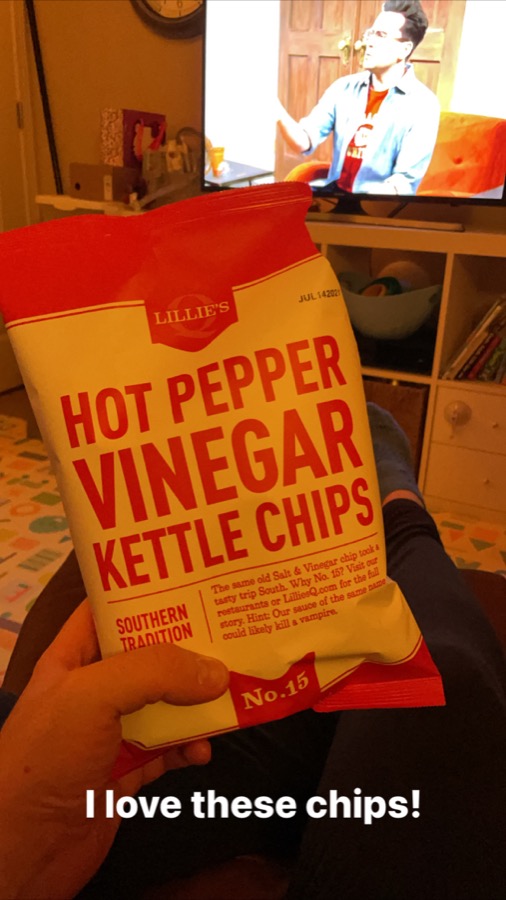 Instagram story from February 2021: a hand holding a bag of Hot Pepper Vinegar Kettle Chips in front of the TV, captioned "I love these chips!"