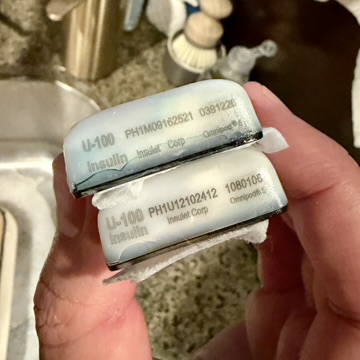 The two old Omnipod 5 pods after I fished them out of the trash, lot numbers visible