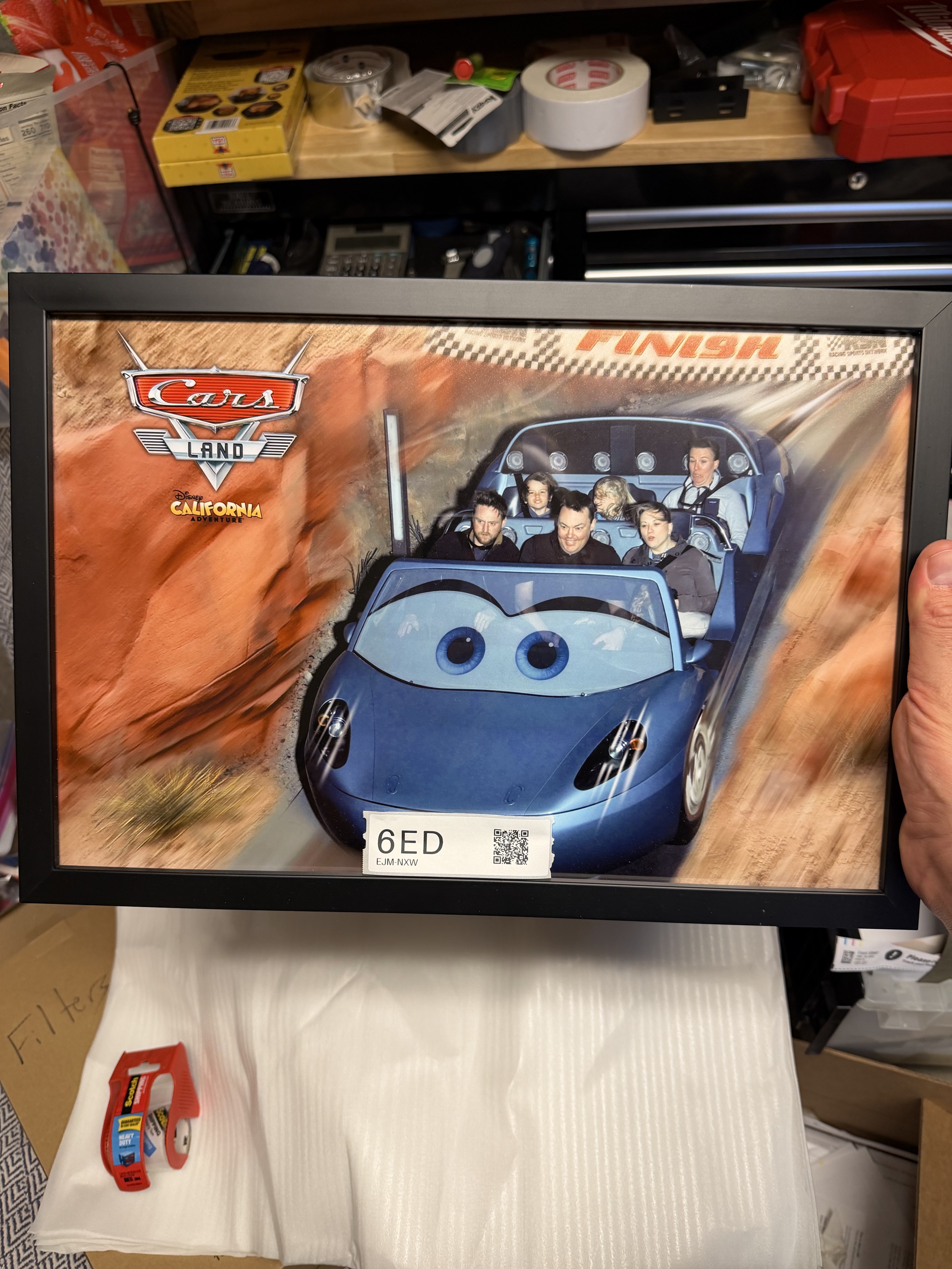 The black-framed Cars Land ride photograph with its 6ED label and QR code visible above the foam packing pockets.