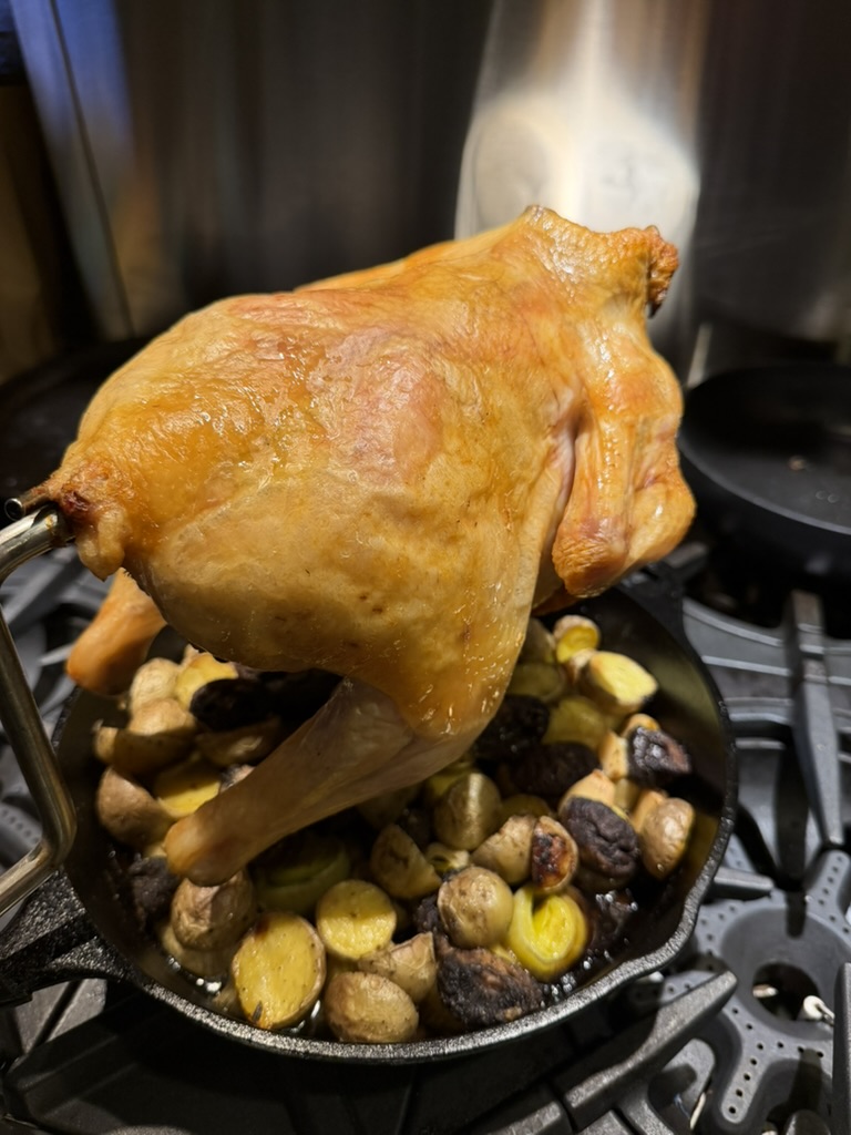 Chicken fresh from the oven on the PoulTree, steam rising, potatoes below